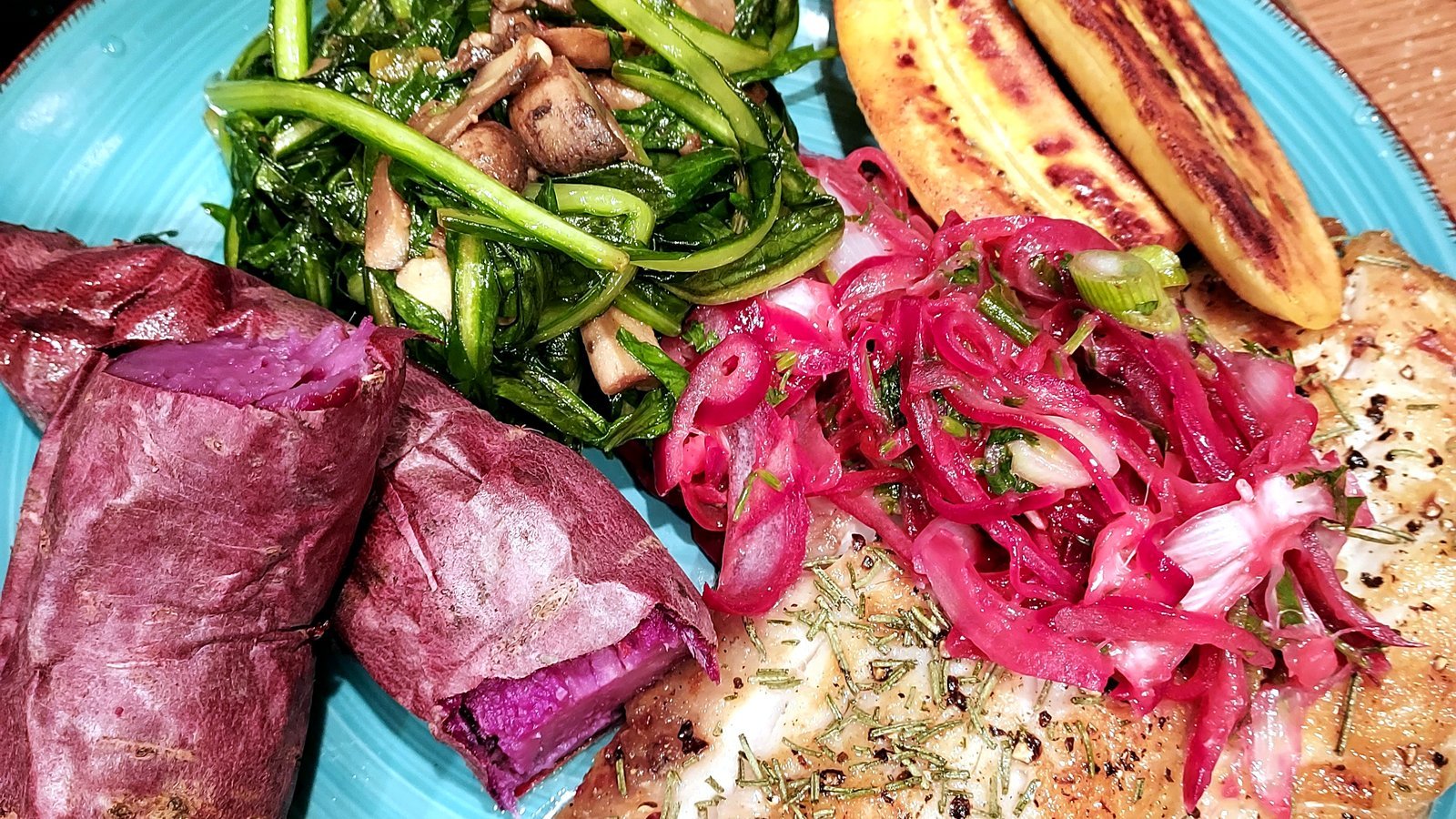 Plated fish with sauteed greens, purple sweet potato, and pickled onion