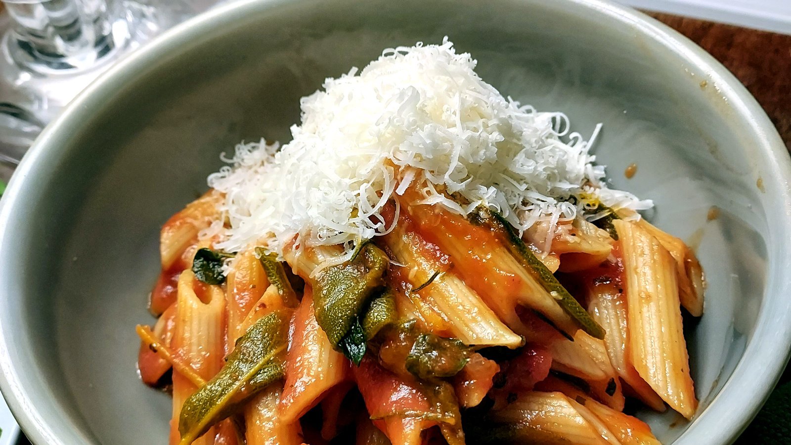 Penne pasta in tomato sauce topped with shaved parmesan
