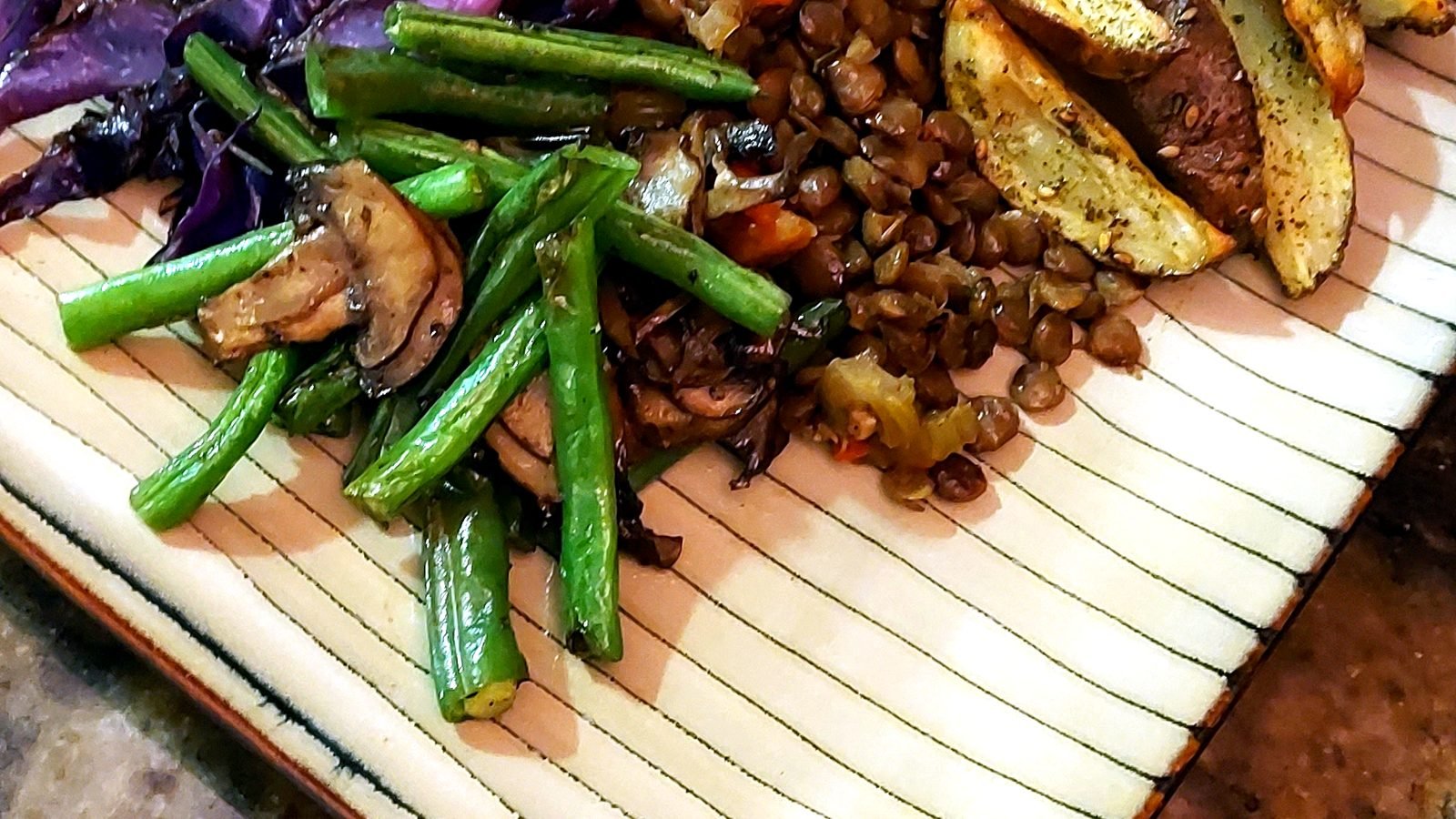 Roasted vegetables, lentils, and greens on a serving board